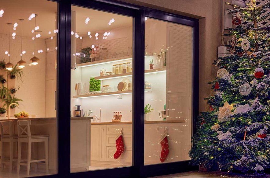 Christmas tree on the patio of an apartment with sliding winter doors in black frame and glass.